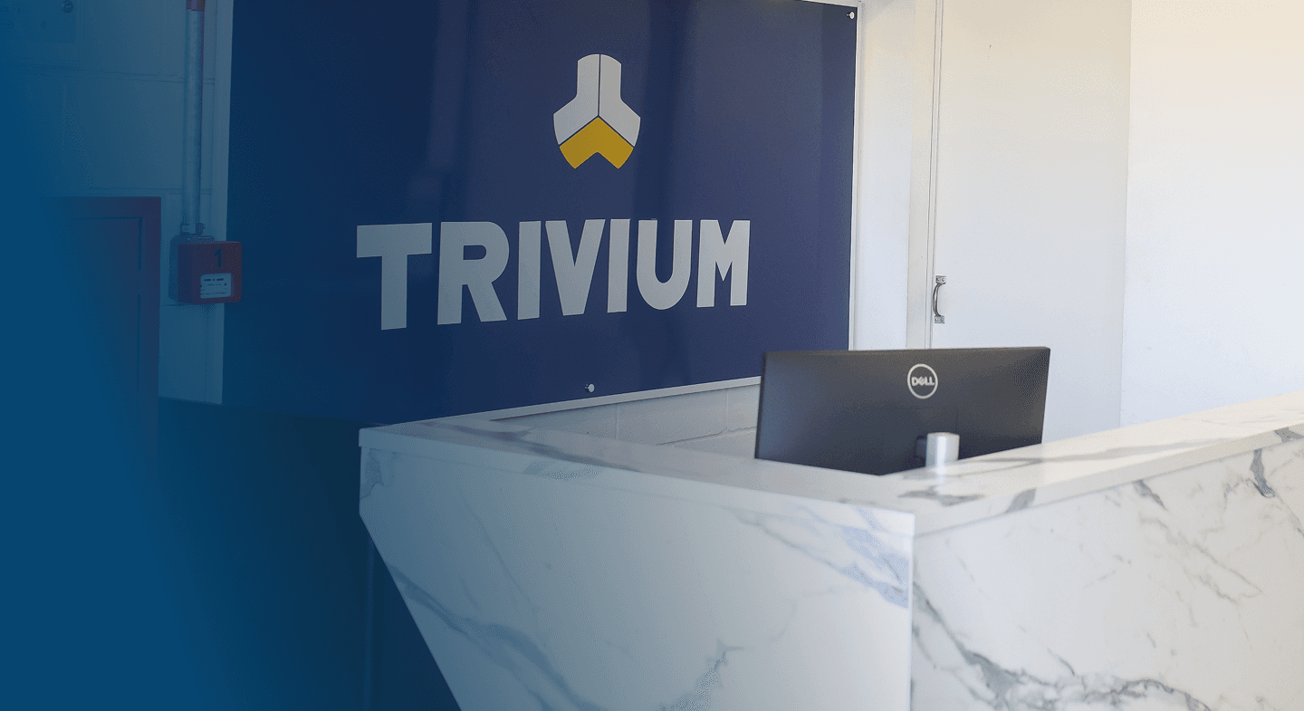Mesa de atendimento na recepção da Trivium, com o logo da empresa ao fundo.